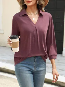 Detailansicht eines burgunderfarbenen V-Ausschnitt-Pullovers mit Jeans und Accessoires.
