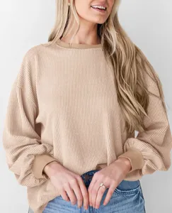 Detailopname van de beige geribbelde textuur op een losvallend sweatshirt met lange mouwen