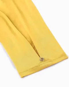 Detail view of a yellow 3/4 sleeve blouse with a stylish slit and decorative metal button.