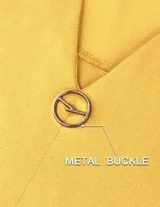 Close-up detail of the stylish circular metal buckle on a yellow women's V-neck blouse.