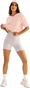 Ganzkörperansicht einer Frau in rosa lockerem Yoga-T-Shirt und weißen Radlerhosen.
