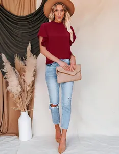 Detail of wine red ruffled mock neck blouse styled with distressed jeans and accessories
