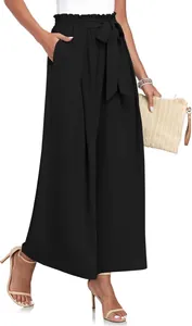 Détail d'un pantalon large noir élégant avec taille haute plissée et ceinture à nœud décoratif.