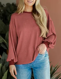 Gedetailleerde weergave van de wafelgebreide textuur op een roze casual top met lange mouwen.