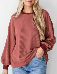 Close-up van geribbeld terracotta sweatshirt met ballonmouwen en een losse pasvorm