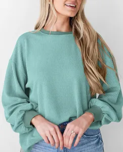 Gedetailleerd beeld van de teal ribstructuur op een ruimvallend sweatshirt met lange mouwen