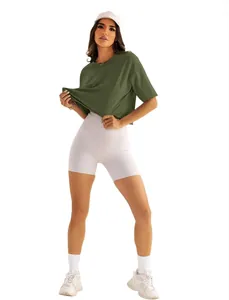 Sportliche Frau in lockerem olivgrünem Yoga-T-Shirt und weißen Fitness-Shorts in Vollansicht