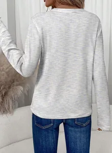 Achteraanzicht van een vrouw in wit wafelgebreid T-shirt met lange mouwen en textuur