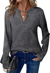 Detailweergave van een dames top met lange mouwen en V-hals met glinsterende textuur.