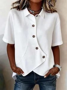 Close-up of white linen-blend shirt featuring an asymmetric hem and wooden buttons.