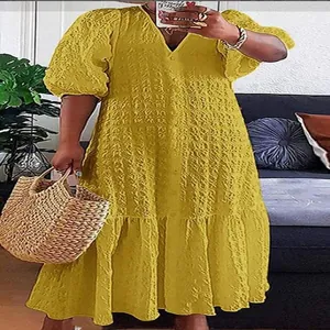 Detailweergave van een gele jurk met V-hals, knopen en getextureerde crinkle-stof