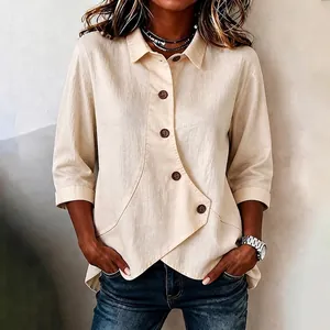 Detailweergave van beige blouse met onregelmatige zoom, stoftextuur en knopen zichtbaar