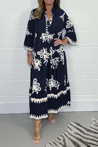 Détail d'une robe longue bleu marine à imprimé fleuri avec col montant et poignets à volants.