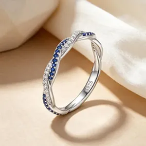 Primo piano di un anello a spirale in argento S925 con pavé di pietre blu e marchio
