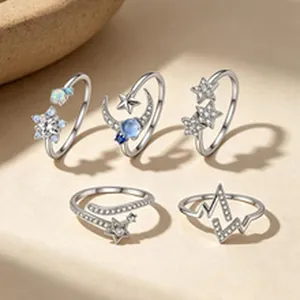 Dettaglio di anelli celesti in argento con design di stelle, luna e battito cardiaco.
