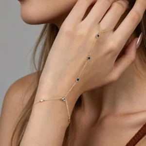 Dettaglio di elegante bracciale schiava placcato oro con pietre blu e bianche sulla mano