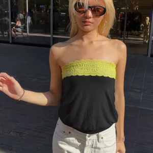 Detail shot of a trendy tube top with yellow lace detailing and black bodice