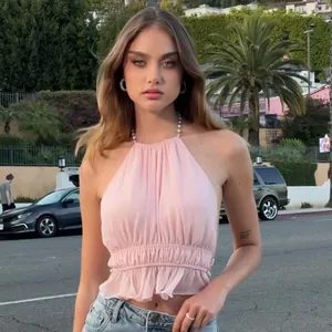 Vista esterna di un sexy top rosa a pieghe con eleganti spalline di perle