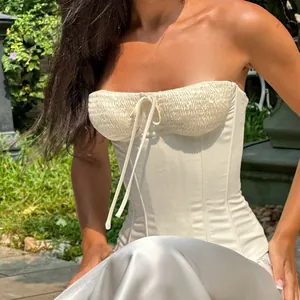 Detailed front view of a white strapless corset top featuring a smocked bust and delicate tie