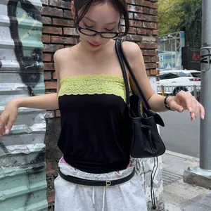 Detail view of a black tube top with yellow lace trim worn in a street style setting.