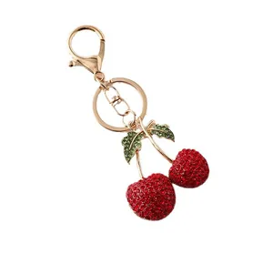 Elegante goudkleurige sleutelhanger met fonkelende rode kersen van strassteentjes
