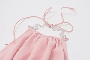 Dettaglio ravvicinato di un top rosa con elegante catena di perle e trama plissettata