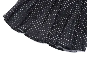 Close-up detail of black mesh fabric with white polka dots and delicate pleated hemline