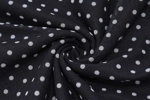 Detailed macro shot of black mesh fabric featuring a classic white polka dot pattern design