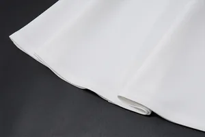 Close-up of the white dress hem showing fine stitching and smooth fabric texture.