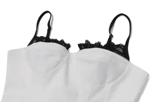 Detailed view of white corset top featuring delicate black lace trim and adjustable straps.