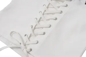 Close-up of a white lace-up cropped top with silver metal eyelets and fabric texture.
