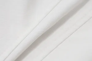 Macro view of white fabric texture and precise stitching on women's summer camisole