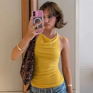 Stylish woman wearing a yellow cowl neck halter top with an open back and leopard bag.
