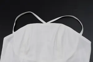 Dettaglio ravvicinato di un top bianco con spalline sottili incrociate
