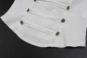 Dettaglio ravvicinato del top corto bianco con bottoni decorativi in bronzo e cinturini