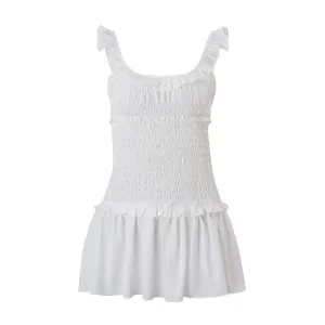 Detalle de minivestido blanco con volantes y cuerpo elástico fruncido.