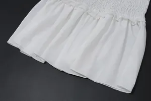Detalle que muestra la fina textura plisada y el dobladillo con volantes de un vestido blanco