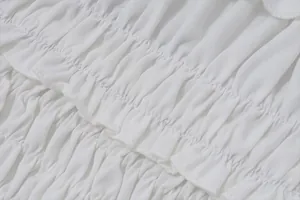 Primer plano detallado de tela blanca fruncida con volantes y pliegues elegantes