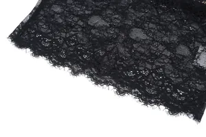 Dettaglio macro del tessuto in pizzo floreale nero con un delicato bordo a ciglia