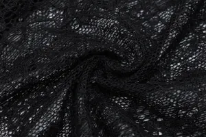 Dettaglio macro di tessuto in pizzo nero trasparente che mostra trame intricate.