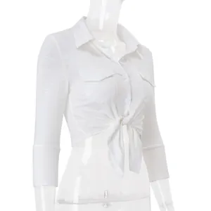 Close-up detail of white cropped women shirt with front tie knot and lapel collar