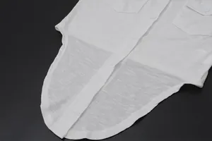 Close-up of a white button-down blouse showing textured fabric, buttons and curved hem.
