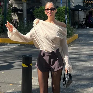 Detailansicht einer Frau in einem sexy beigen Off-Shoulder-Netztop mit Blumenakzent