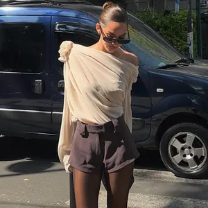 Modell trägt aprikosenfarbenes schulterfreies Chiffon-Top mit Blumendetail auf der Straße