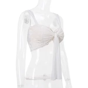 Dettaglio di un top a fascia in pizzo e mesh bianco con grande fiocco frontale