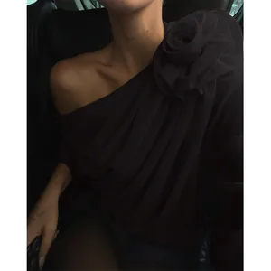 Detailansicht eines schwarzen schrägen Chiffon-Tops mit großer Rosenblüten-Dekoration