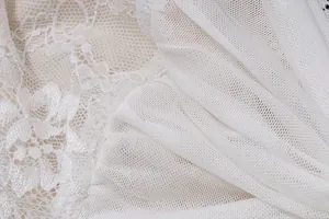 Dettaglio macro di pizzo floreale bianco e mesh delicata per top a fascia da donna.