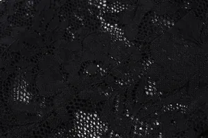 Macro view of intricate black floral lace fabric with delicate hollow-out texture