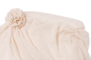 Detailansicht eines cremefarbenen Chiffon-Tops mit großer 3D-Blume und eleganter Faltenstruktur.