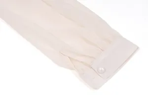 Detaillierte Nahaufnahme einer plissierten Chiffon-Manschette mit elegantem Perlenknopf